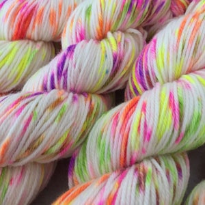 May include: White yarn with bright pink, orange, yellow, and green speckles. The yarn is twisted and piled together.