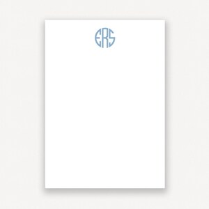 May include: A white notepad with a blue monogram of the letters "ERS" in a circle.