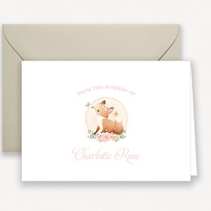 May include: A white card with a pink fox illustration and floral accents. The text "From the nursery of Charlotte Rose" is printed in pink.