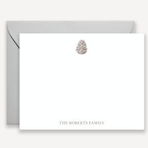 May include: A white card with a silver pine cone design and the text "THE ROBERTS FAMILY" at the bottom.