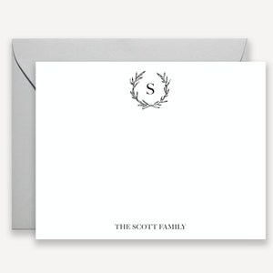 May include: A white stationery card with a black floral wreath and the letter "S" in the center. The text "THE SCOTT FAMILY" is printed at the bottom of the card.