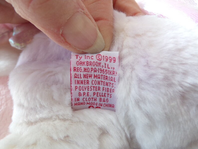 Peut inclure: &Eacute;tiquette en tissu rose et blanc avec le texte "Ty Inc 1999 Oakbrook, IL, Reg. No. PA 1965(KR) All New Material Inner Contents Polyester Fiber & P.E. Pellets in Cloth Bag Hand Made in China"