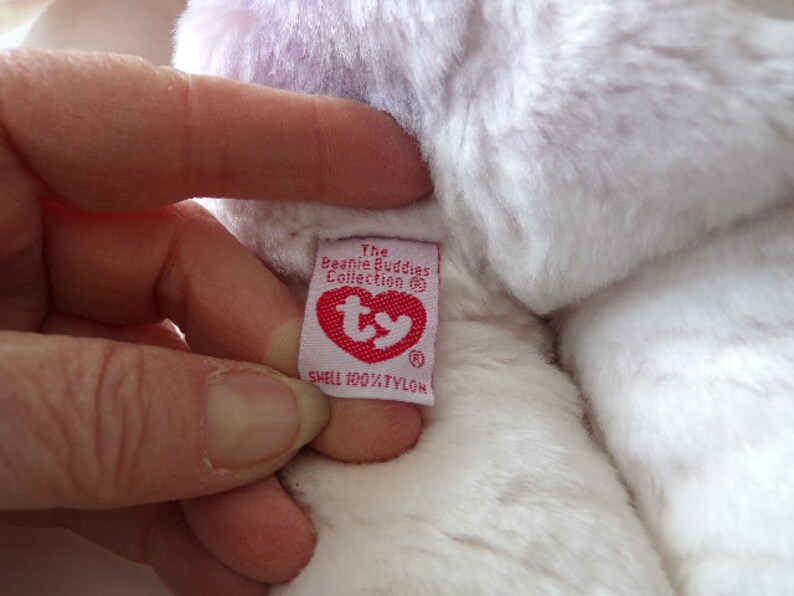 Peut inclure: Peluche blanche et violette avec une &eacute;tiquette Ty rouge qui indique "The Beanie Buddies Collection" et "Shell 100% Nylon".