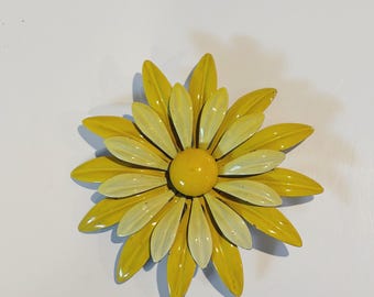 Peut inclure: Une broche en forme de fleur superposée avec deux rangées de pétales pointus. La couche extérieure se compose de pétales jaune vif, tandis que la couche intérieure présente des pétales jaune pâle. Un centre rond jaune complète le design.