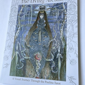 May include: A book titled The Living Arcana: A Visual Journey Through the Paulina Tarot. The cover features a central figure with multiple eyes, surrounded by ethereal beings, trees, and a pomegranate, all rendered in shades of blue and brown.