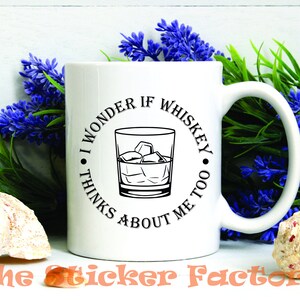 Pu&ograve; includere: Tazza da caff&egrave; in ceramica bianca con una grafica nera che recita "Mi chiedo se il whisky pensa anche a me." La grafica include un bicchiere di whisky con cubetti di ghiaccio.