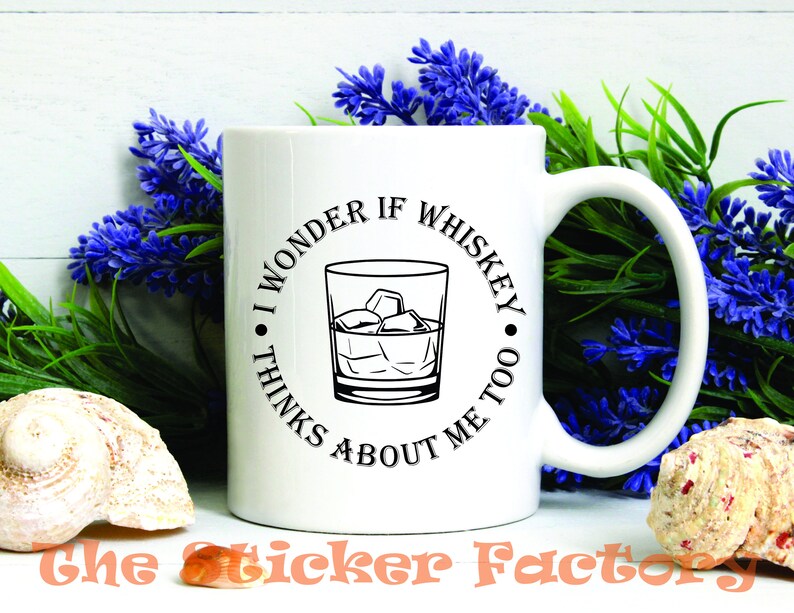 Pu&ograve; includere: Tazza da caff&egrave; in ceramica bianca con una grafica nera che recita "Mi chiedo se il whisky pensa anche a me." La grafica include un bicchiere di whisky con cubetti di ghiaccio.
