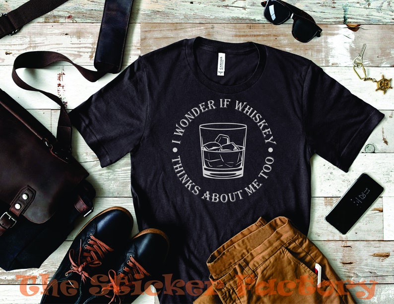 Pu&ograve; includere: Una maglietta nera con un design grafico bianco di un bicchiere di whisky con cubetti di ghiaccio. Il testo sul grafico dice "Mi chiedo se il whisky pensa anche a me."