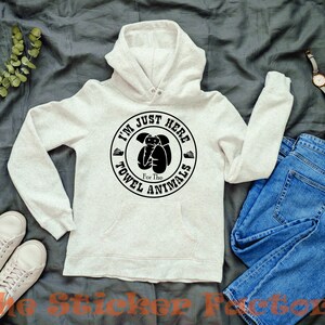May include: A light gray hooded sweatshirt with a black circle graphic that says "I'm Just Here For The Towel Animals".