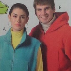 May include: A woman and a man are wearing outerwear. The woman is wearing a teal zip-up vest over a yellow turtleneck. The man is wearing a red hooded jacket over a white turtleneck. The image is a close-up shot.