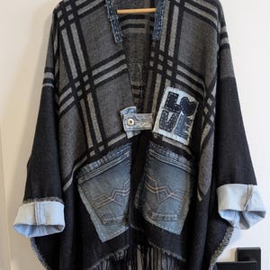 May include: A distinctive poncho in grey and black plaid, with denim pockets and cuffs. The garment has a fringed hem and a patch with the word "LOVE".