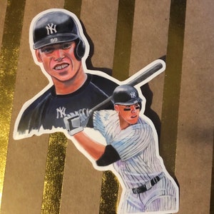 May include: A sticker featuring a watercolor illustration of a baseball player wearing a New York Yankees uniform. The player is holding a bat and is in a batting stance. The sticker also features a smaller image of the player's face in the background.