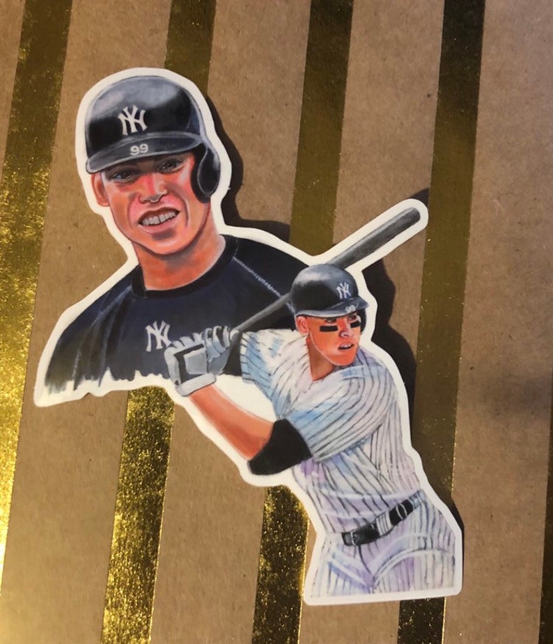 May include: A sticker featuring a watercolor illustration of a baseball player wearing a New York Yankees uniform. The player is holding a bat and is in a batting stance. The sticker also features a smaller image of the player's face in the background.