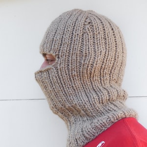 May include: A beige knitted balaclava with a hole for the eyes and mouth.