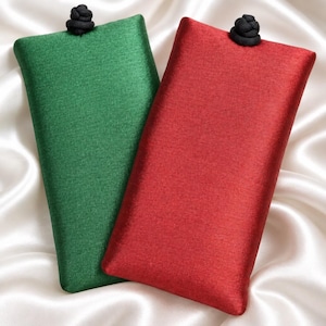 May include: Two rectangular fabric pouches, one in emerald green and one in deep red, each featuring a smooth, slightly iridescent finish and a small, black, rounded knot closure at the top center of the opening, providing a secure storage solution.