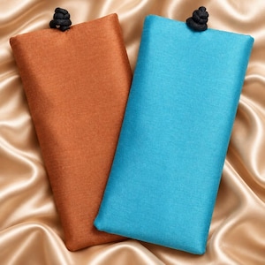 May include: Two rectangular fabric pouches, one in a burnt orange color and the other in a bright turquoise blue. Each pouch features a smooth, woven texture and is topped with a small, black knotted cord closure at the center of the top edge.