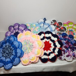 May include: A collection of nine crocheted flower-shaped pot holders in various colors, including blue, purple, pink, yellow, white, red, and green.