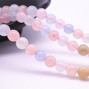 May include: A strand of round, pastel-colored beads. The beads are pink, light blue, and white. The beads are strung on a clear thread.