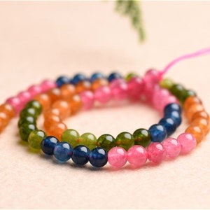 May include: A multi-coloured beaded necklace with pink, green, orange, and blue beads. The beads are round and have a smooth, polished finish.