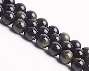 May include: A strand of black and gold gemstone beads. The beads are round and have a smooth, polished finish. The beads are strung on a clear thread.
