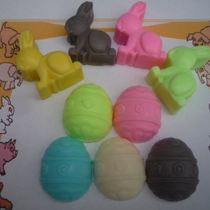 May include: Assortment of Easter-themed bunny and egg-shaped soaps in various colours, including pink, yellow, green, brown, and white. The soaps are arranged on a white surface with a decorative border.