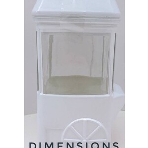 May include: White ceramic popcorn cart with a glass window and a wheel. Dimensions: 8.5" H x 4.5" W.