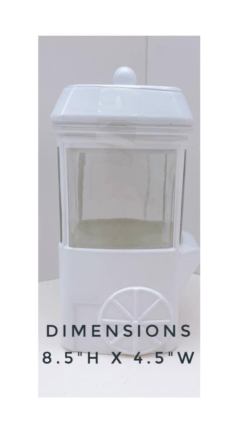 May include: White ceramic popcorn cart with a glass window and a wheel. Dimensions: 8.5" H x 4.5" W.