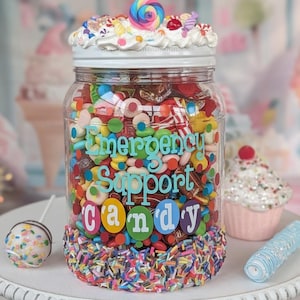 May include: A clear glass jar filled with colorful candies, decorated with the words "Emergency Support Candy." The jar is topped with whipped cream and a rainbow swirl lollipop. A cake pop and cupcake are also visible.