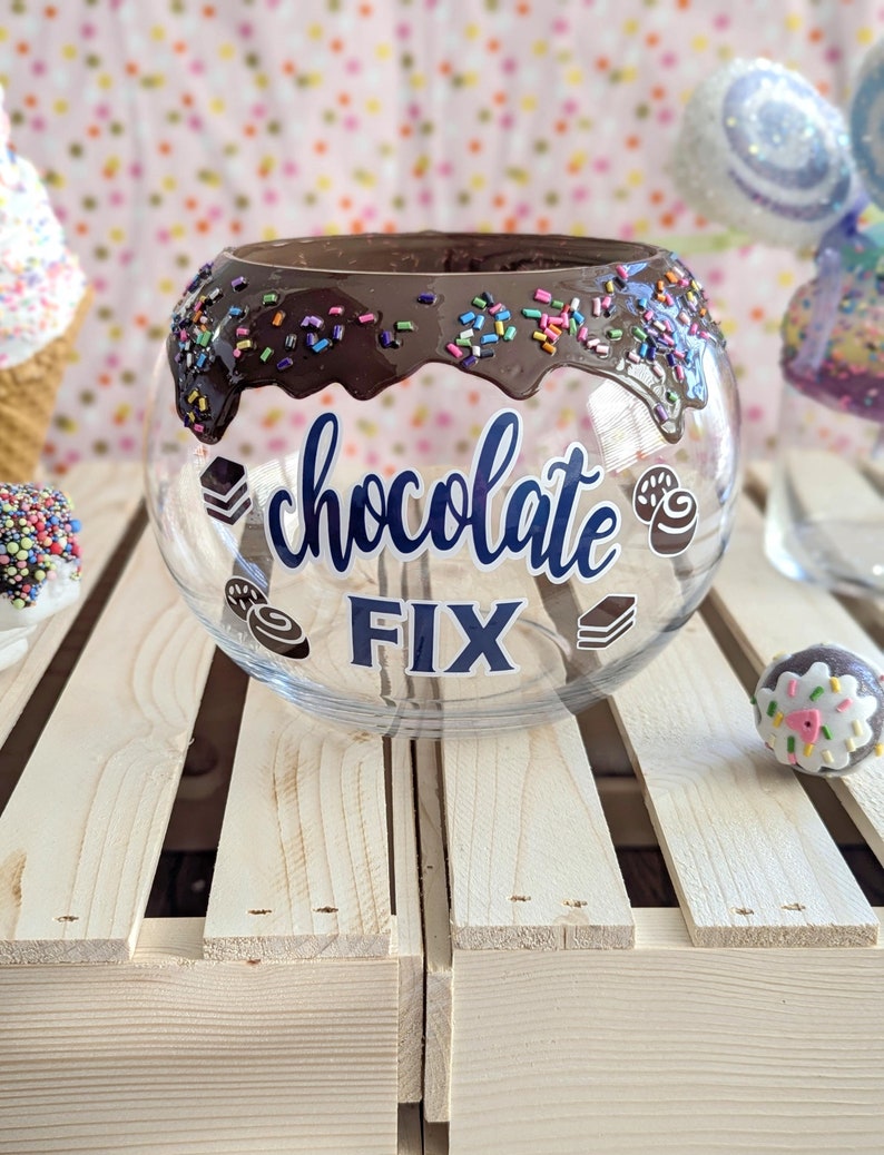 May include: A clear glass bowl with a chocolate rim and sprinkles. The bowl has the words "chocolate fix" written on it.