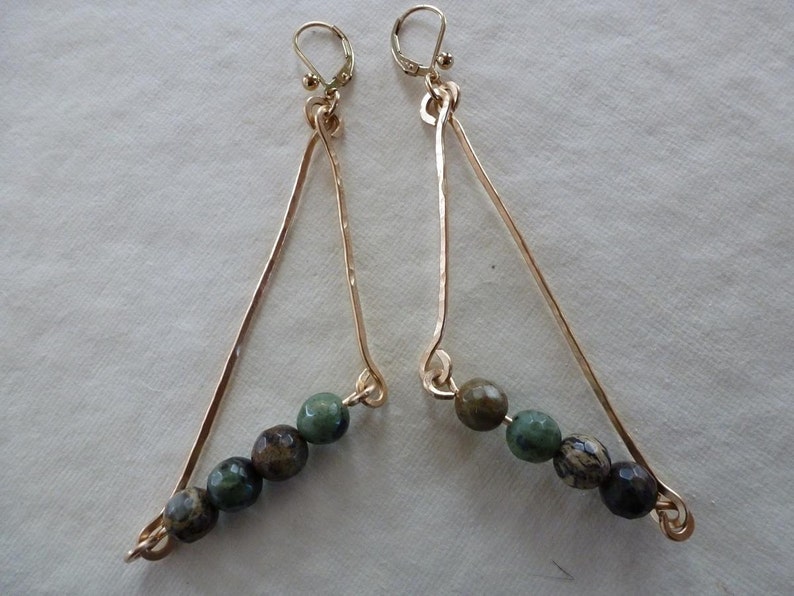 May include: Gold triangle shaped earrings with green and brown gemstone beads.