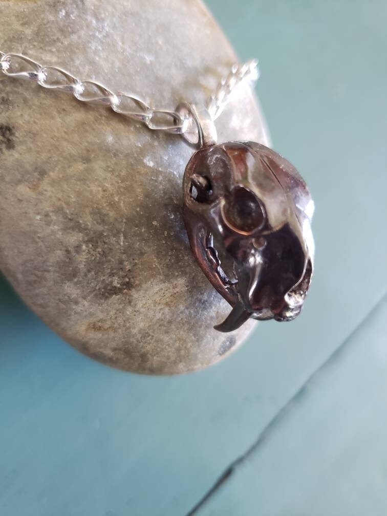 Smilodon Skull Necklace packs a Pleistocene punch on twisted silver links. Bob Burkett shibuichi sabertooth cat skull with articulated jaw.