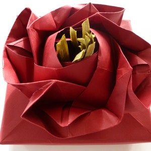 May include: A red origami rose with a center made of dried leaves.