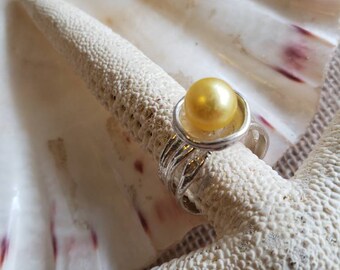 Gold And Silver Treasure Ring cups an 8.5mm South Sea pearl in an organic silver ring, casting a golden glow! A beautiful statement, size 8.