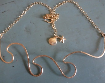 The Third Wave Necklace is a gold handshaped and hammered triple wave on gold chain to adjust from 24 inches up. Gold charms and hook.