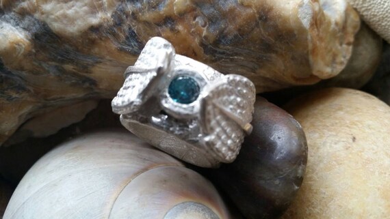 Leafy Blue Ring is a 999 fine silver wide band showcasing a round faceted blue topaz flanked by dimensional silver leaves. Lots of texture!