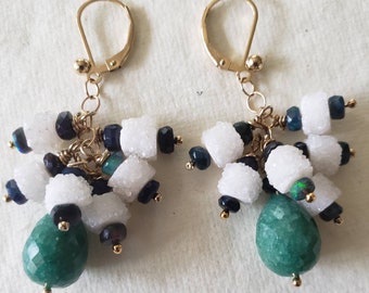 Puede incluir: Pendientes de oro con cuentas de piedras preciosas blancas, verdes y azules. Los pendientes tienen una piedra preciosa verde en forma de lágrima en la parte inferior.