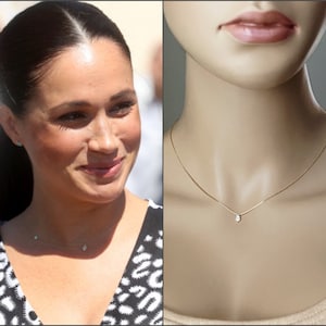 May include: A delicate gold chain necklace with a single small diamond pendant. The necklace is shown on a mannequin.