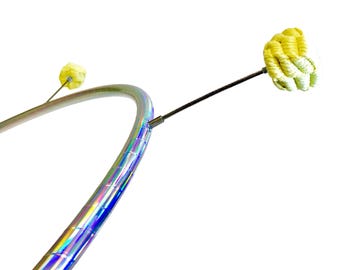 May include: A silver and iridescent hula hoop with a black rod and a yellow, spherical fire poi. The fire poi is made of a woven material. The hula hoop is curved and has a reflective, rainbow-like finish.