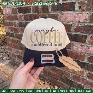 May include: A two-tone baseball cap with a cream-coloured crown and a black brim. The front features embroidered text that reads maybe COFFEE is addicted to me. A rectangular sticker is on the brim, and a cloud-shaped brown tag is attached.