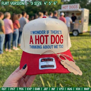 May include: A cream-coloured baseball cap with a red brim featuring the embroidered blue and red text: I WONDER IF THERE'S A HOT DOG THINKING ABOUT ME TOO. A rectangular sticker on the brim reads CLASSIC FIT 05FM MID PROFILE MAXIMUM COMFORT.