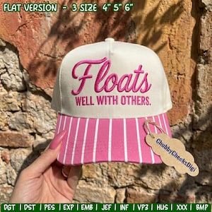 May include: A cream-coloured baseball cap with pink embroidered script reading Floats WELL WITH OTHERS. The brim features a pink and white vertical striped pattern. A tan, cloud-shaped paper tag labelled ChubbyCheeksDigi is attached.