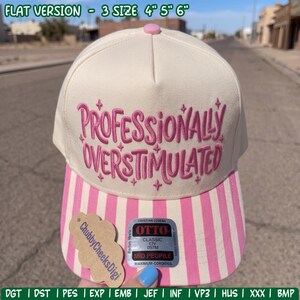 May include: A cream-colored baseball cap featuring pink embroidered text that reads Professionally Overstimulated with small star accents. The brim has vertical pink and white stripes. A sticker on the brim displays the brand name Otto.