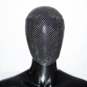 以下が含まれることがあります： ダイヤモンドのパターンが施された黒いメッシュマスク。マネキンの顔を覆っています。