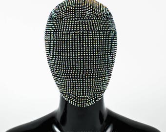 May include: A black face mask covered in iridescent rhinestones. The mask is on a black mannequin head.