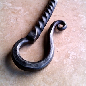 May include: A black metal fireplace poker with a twisted handle and a hook at the end.