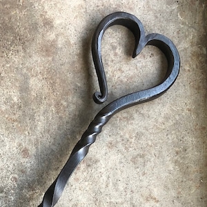 Pode incluir: Uma escova de lareira de metal preto com uma al&ccedil;a em forma de cora&ccedil;&atilde;o e uma base de madeira. A escova &eacute; feita de cerdas naturais.