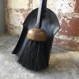 Pode incluir: Um conjunto de lareira de metal preto com uma escova de cabo de madeira e uma p&aacute; combinando. O conjunto &eacute; projetado para limpar lareiras e lareiras.