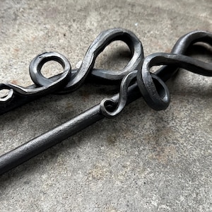May include: Two black metal fireplace tools with decorative, twisted handles. The handles are shaped like a vine or a snake.