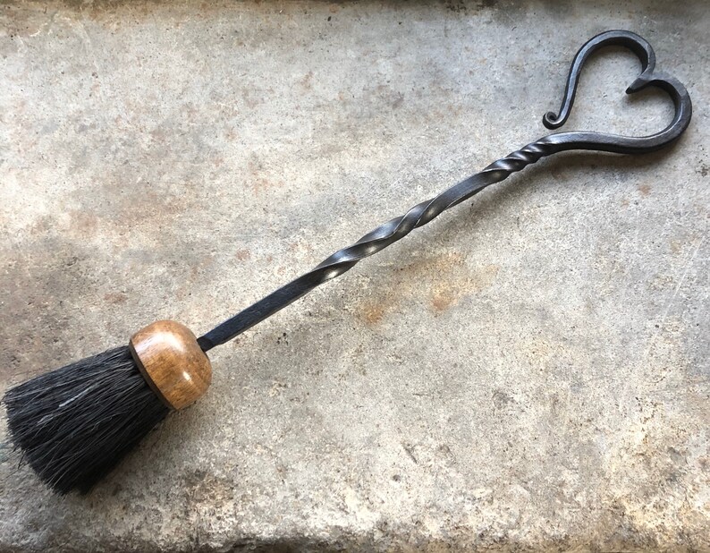 Pode incluir: Uma escova de lareira preta com uma pega de madeira e uma pega de metal em forma de cora&ccedil;&atilde;o.