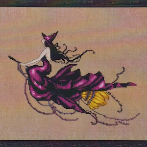 May include: A framed cross-stitch embroidery depicting a figure in a pointed hat and a flowing purple dress riding a broomstick. The figure has long dark hair and is flying against a gradient peach background with yellow broom bristles.